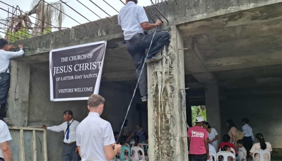 అసంపూర్తి భవనంలో చర్చి బ్యానర్ కడుతూ ఆరాధన సమావేశానికి సిద్ధమవుతున్న మిషనరీలు.